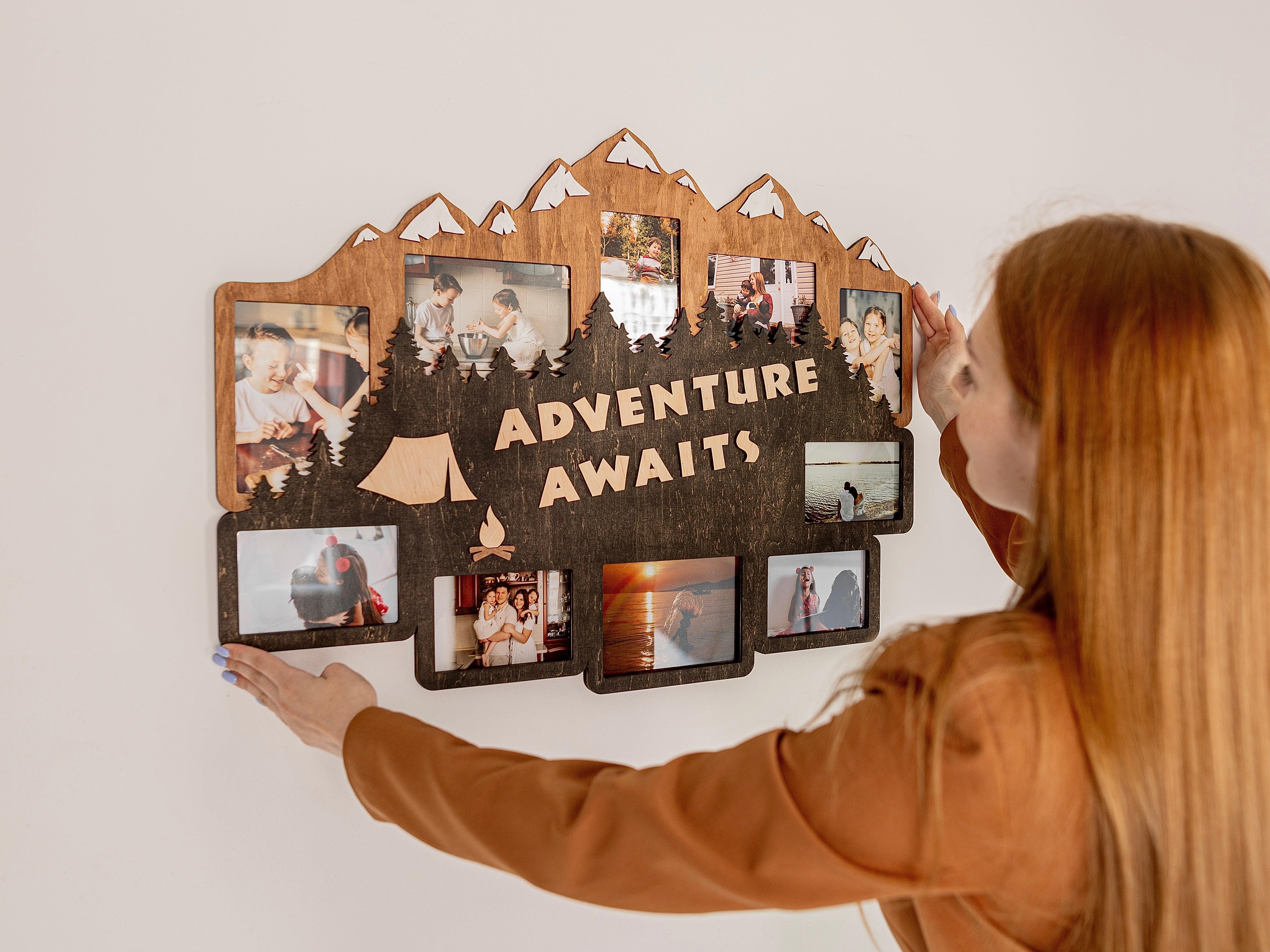 Wooden photo frame collage decorated with mountains, forest, and a tent with fire as well as adventure awaits text in the middle. This collage is 23 by 31 inches and has 10 frames. Trees and mountains can be painted in different colors.