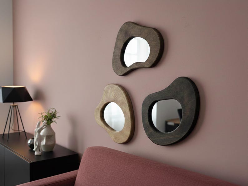 Three pebble-shaped wall mirrors with warm natural wood frames