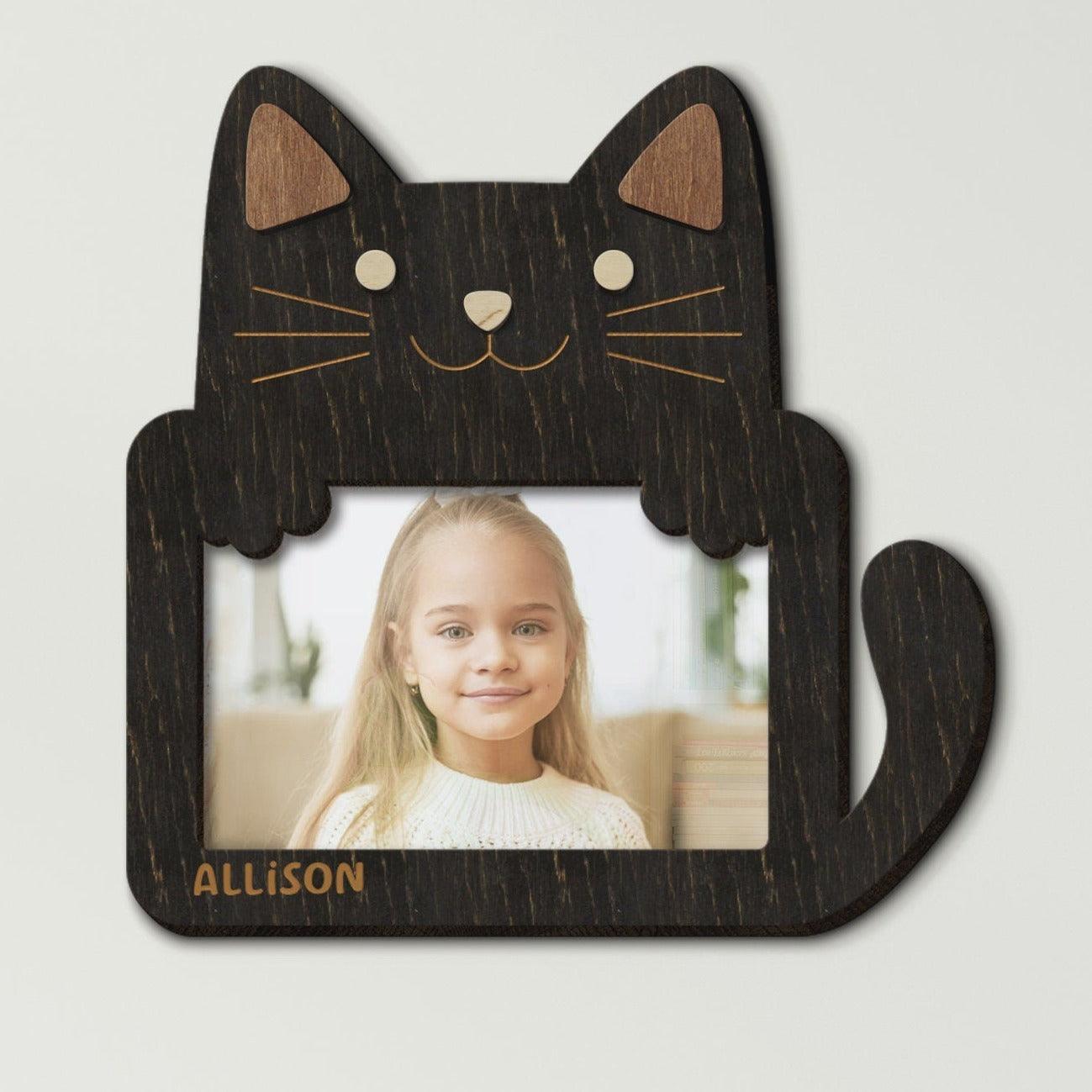 Wooden 4 by 6 inches photo frame in the shape of a cute cat holding a photo. The name is engraved on the bottom left. This frame is 9 by 9 inches and 8 millimeters thick. The cat and ears can be painted in different colors. The name can be changed.